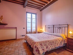 Een slaapkamer met een bed, nachtkastje, raam en radiator.