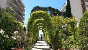 Un chemin bordé de plantes en pot et un bâtiment doté de balcons.