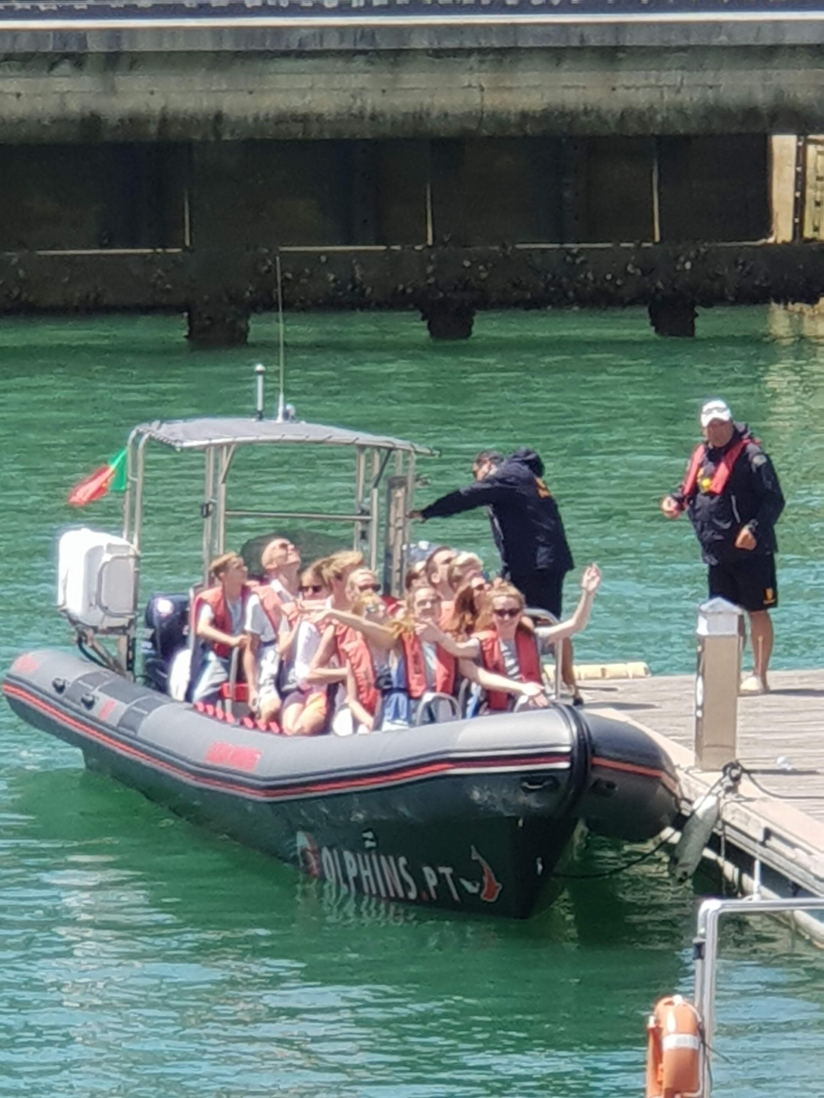 A boat with people wearing life jackets, docked at a pier.