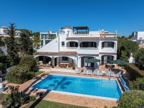 A two-story house with a swimming pool, outdoor seating, and a covered patio.