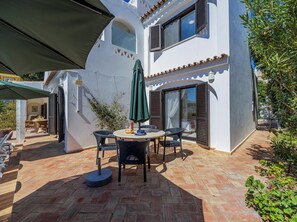 A patio with a round table, chairs, and an umbrella.