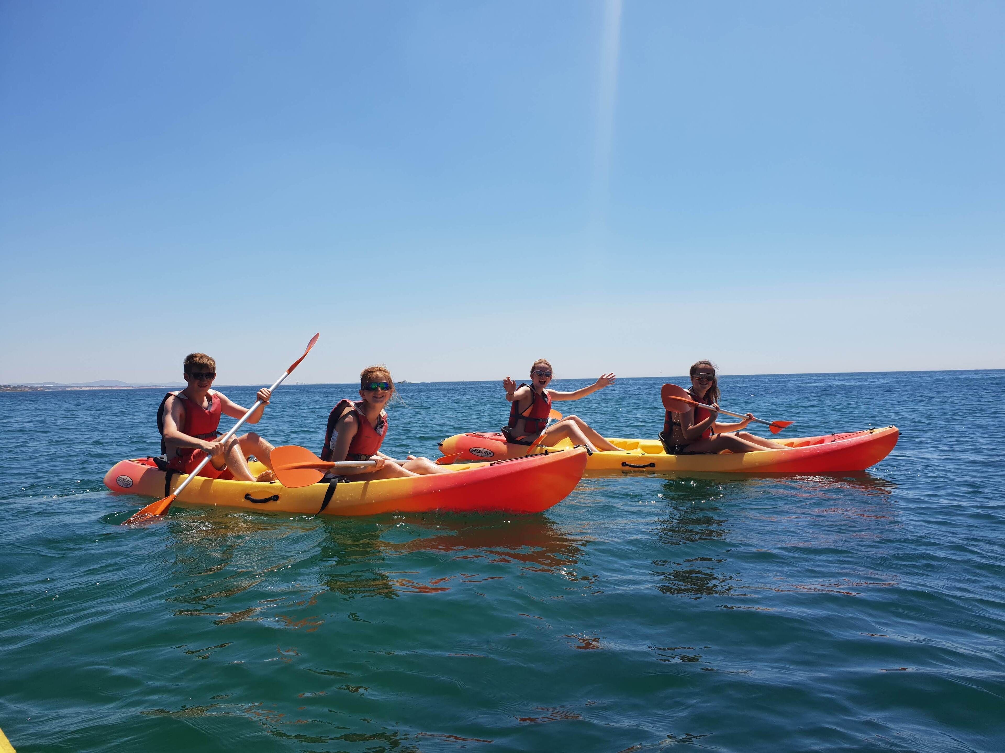 Three people kayaking on a calm sea.