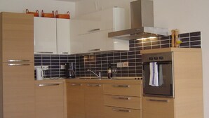 Une cuisine moderne avec des meubles en bois, un four encastré et un dosseret en carreaux noirs.