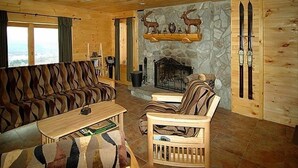 Een gezellig blokhutinterieur met een stenen open haard, houten wanden en een bank.