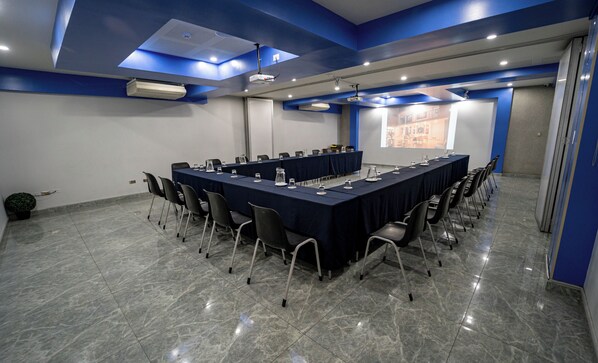 A conference room with a long table, chairs, and a projector screen. - Gran Recreo Hotel (Trujillo)
