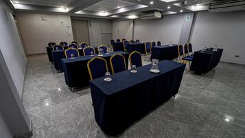 Un salón de conferencias con varias mesas y sillas, equipado con tarjetas de identificación y vasos de agua.