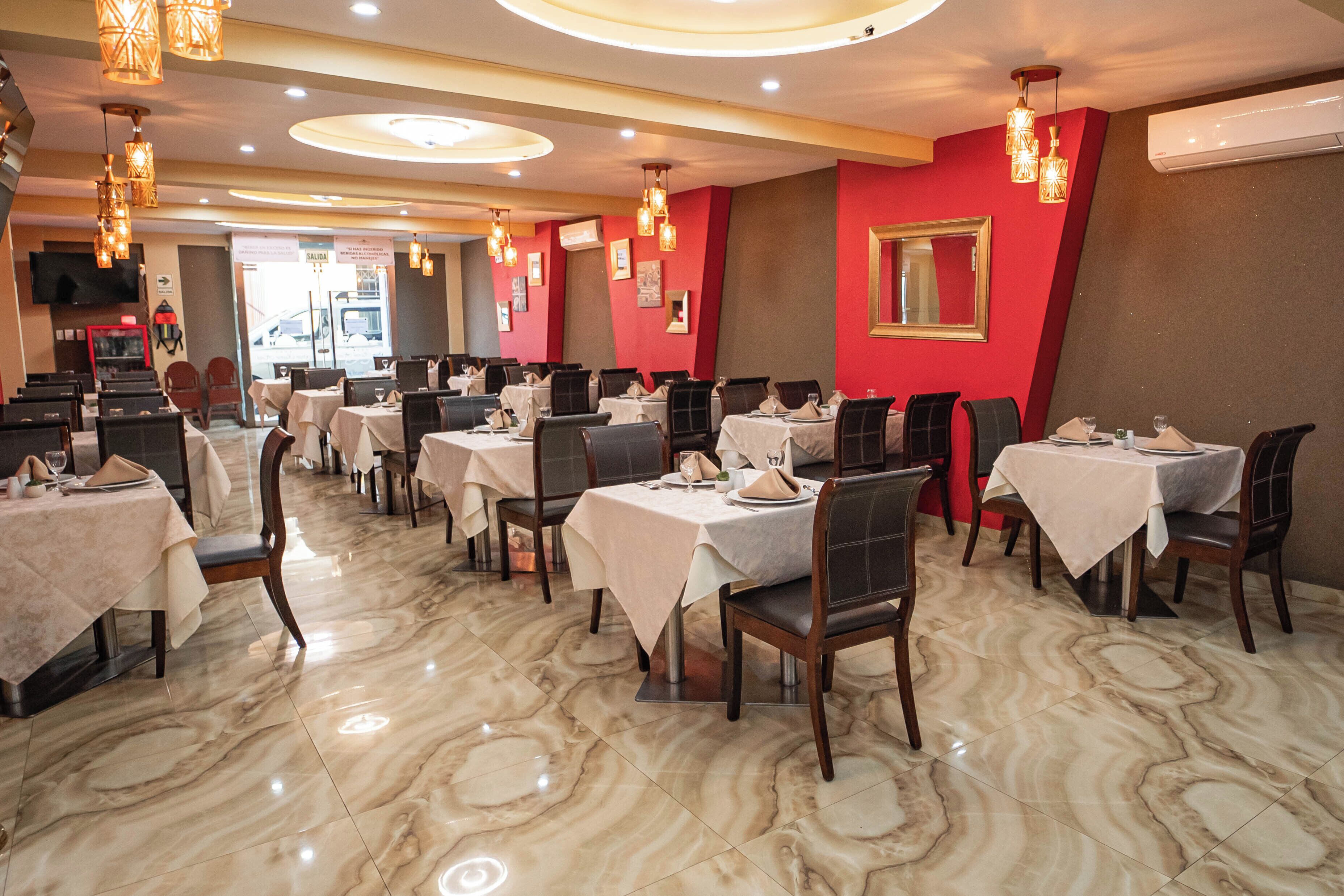 A restaurant with marble flooring, multiple tables with chairs, and hanging pendant lights.