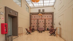 A spacious indoor area with a high ceiling, a glass skylight, a fire extinguisher, a trash bin, and wooden furniture. - Gran Recreo Hotel (Trujillo)