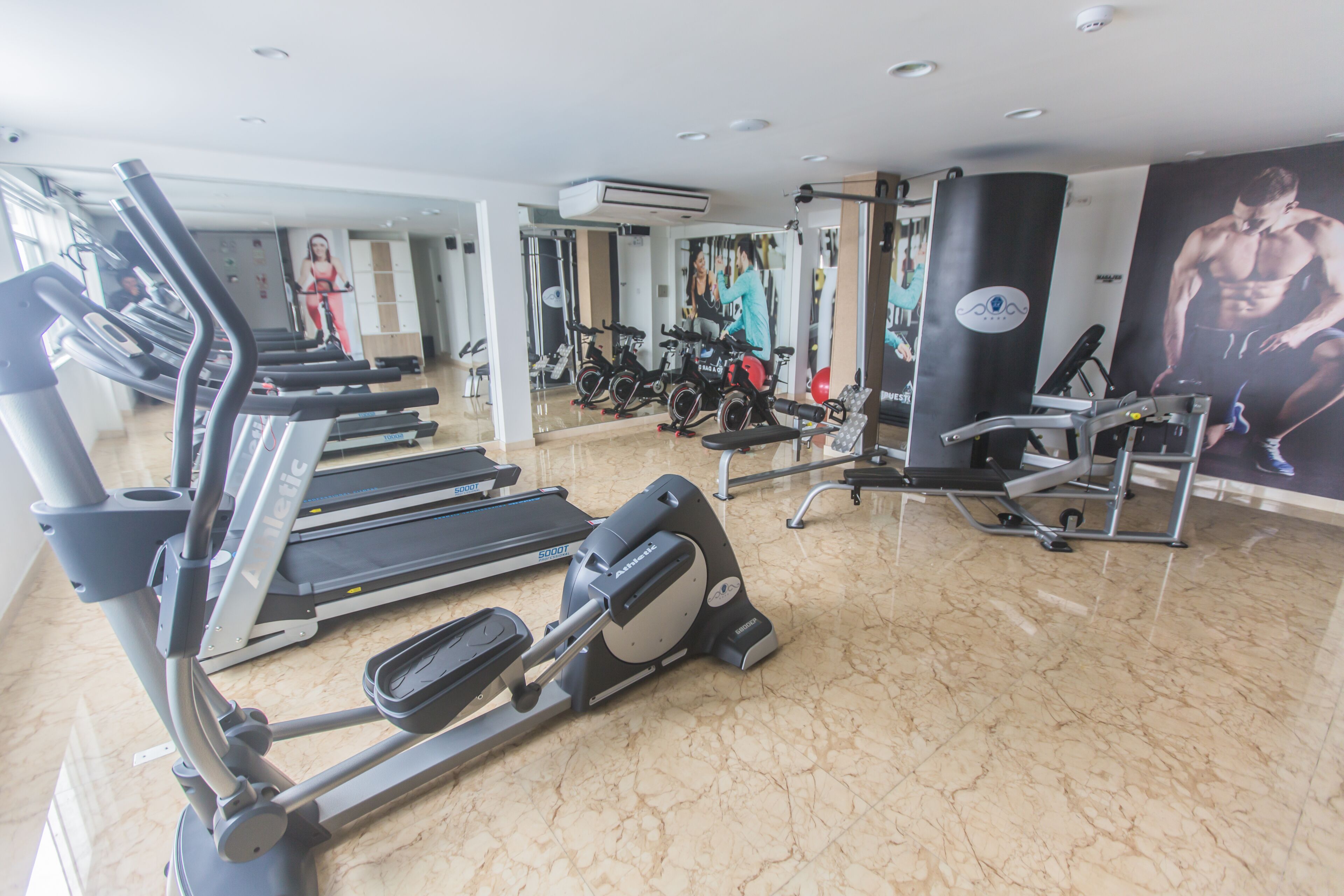 Un gimnasio con cintas de correr, bicicletas estáticas y máquinas de pesas.