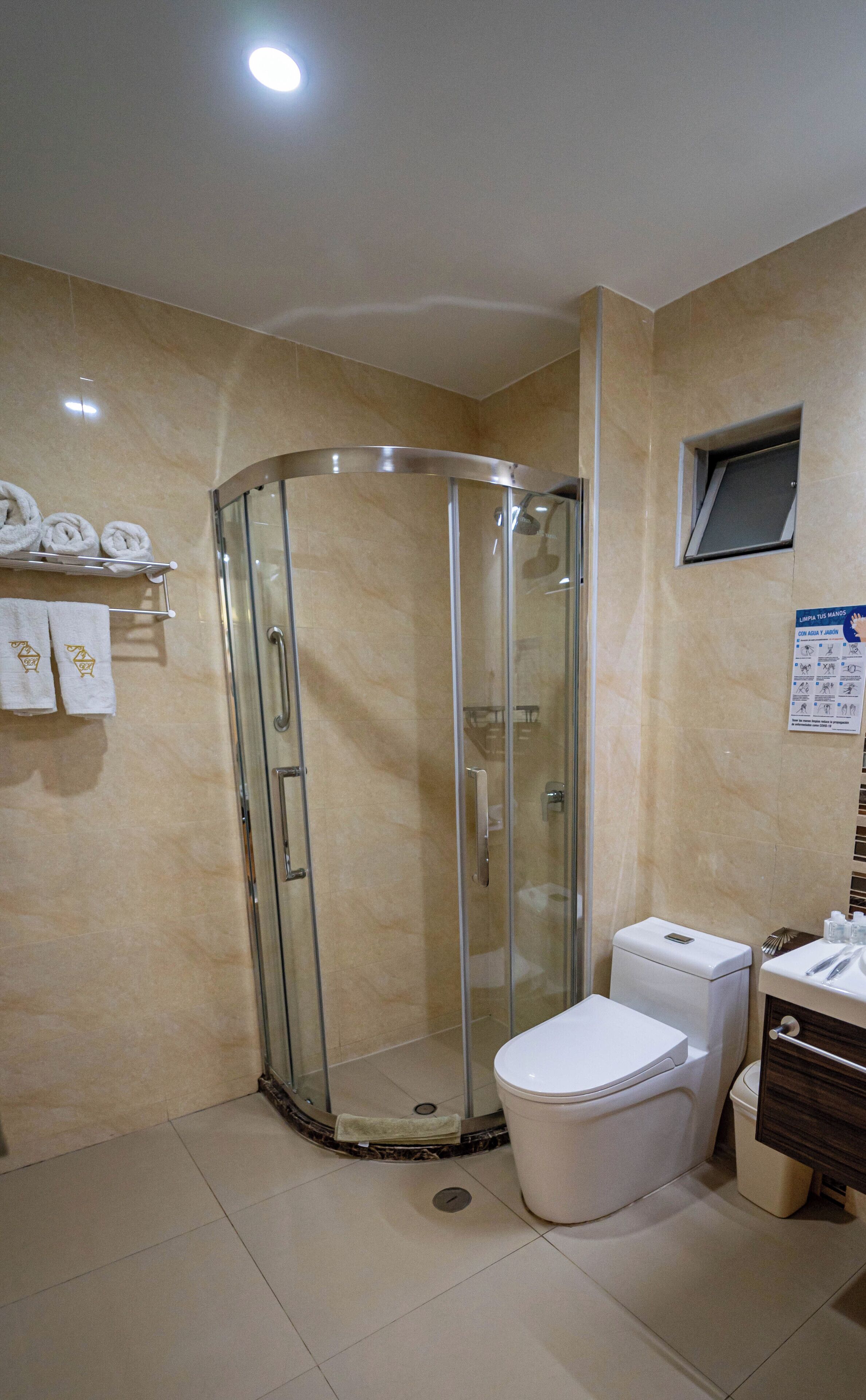 Un baño con ducha envuelta en vidrio, un inodoro y un lavabo.