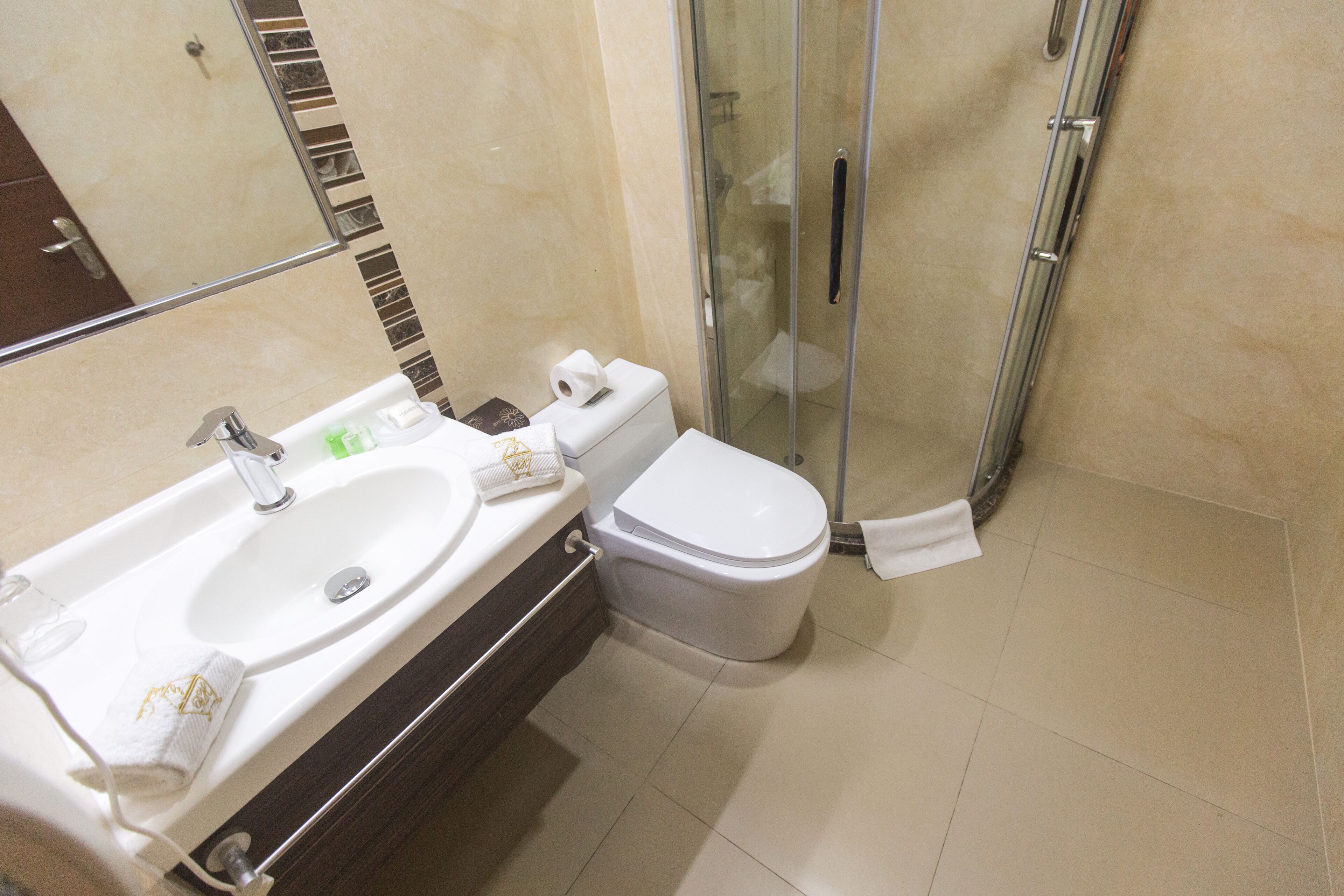A modern bathroom with a double sink, toilet, and glass shower enclosure.