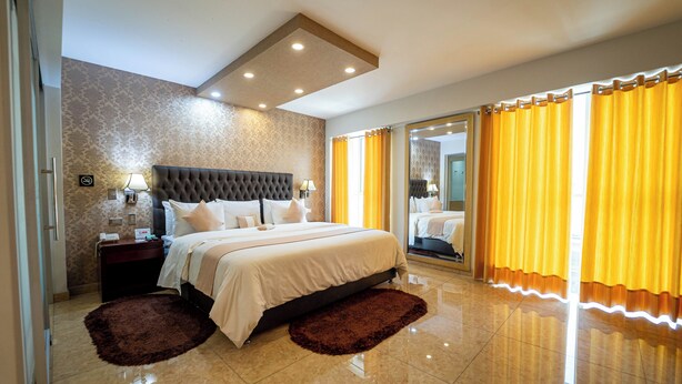 A modern hotel room with a large bed, a nightstand, a mirror, and a bathroom visible through a sliding door. - Gran Recreo Hotel (Trujillo)