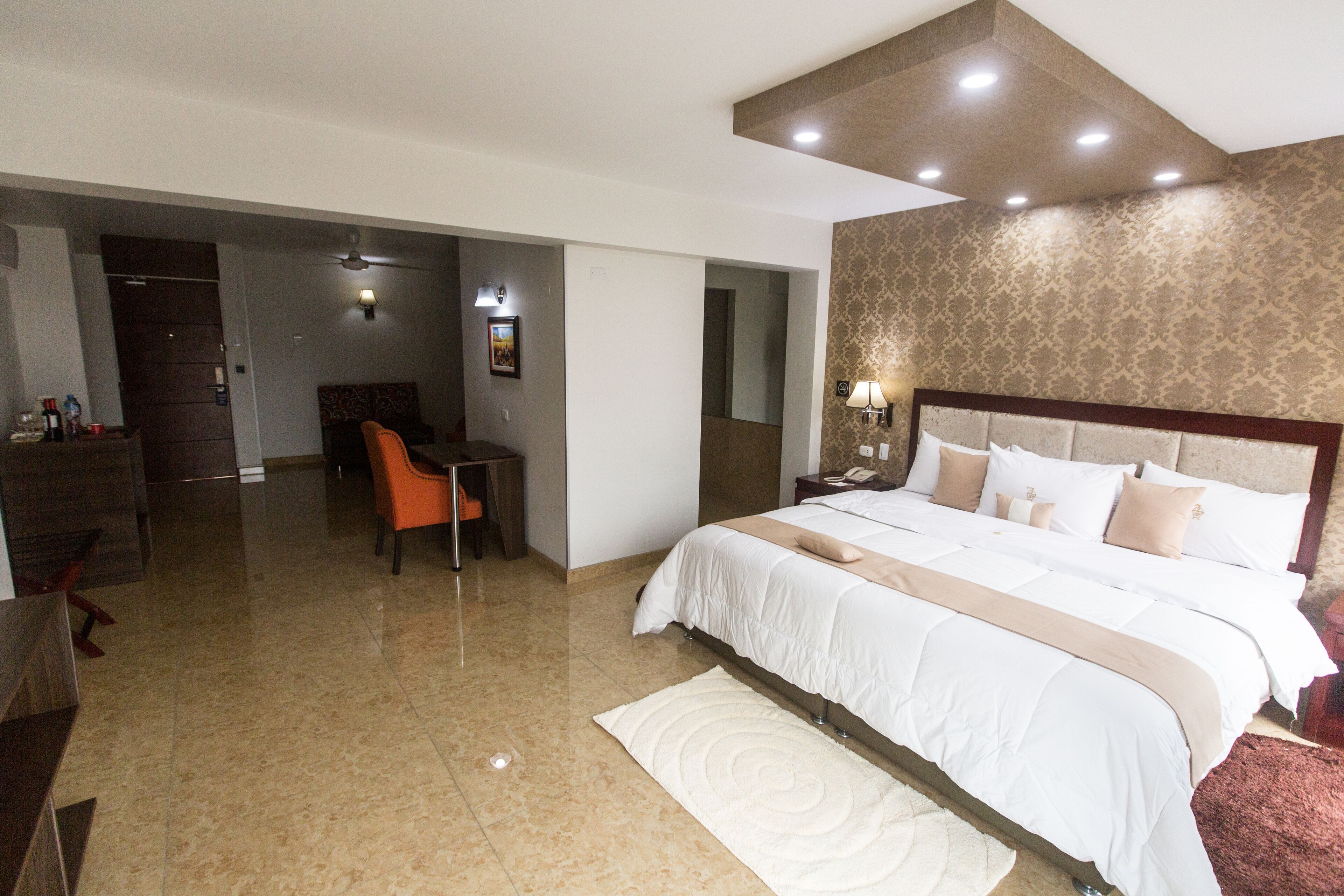 A hotel room with a large bed, a desk, and a chair.