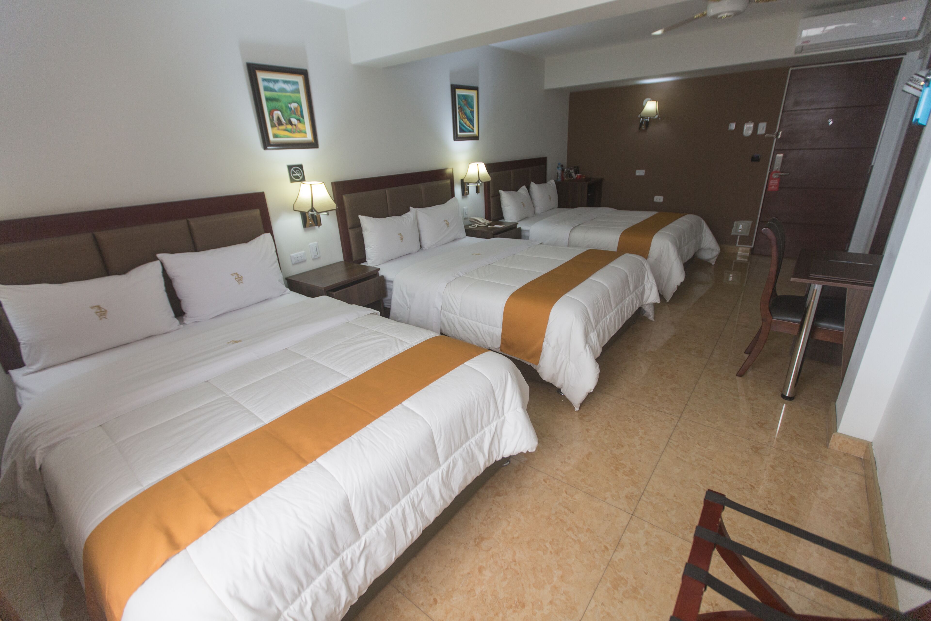 Habitación de hotel con dos camas, un escritorio y una silla.