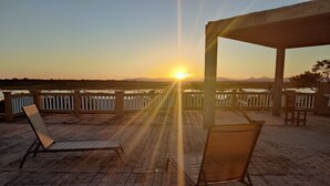 A sunset view from a covered outdoor seating area with brick flooring and white railings. - Savannah Sand Dollar (Hopkins)