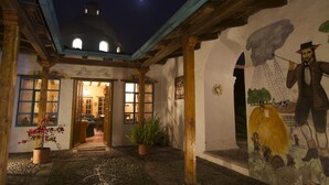 Ein Innenhof mit Wandgemälde, Holzbalken und einem Gebäude mit Kuppel.