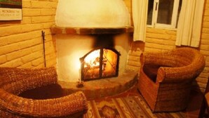 Ein gemütliches Zimmer mit Kaminofen, Korbmöbeln und einem gemusterten Teppich.