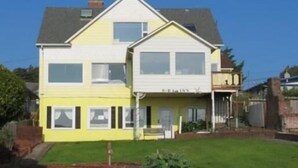 Ein gelbes Haus mit zwei Etagen, einer Garage und einer kleinen Veranda.