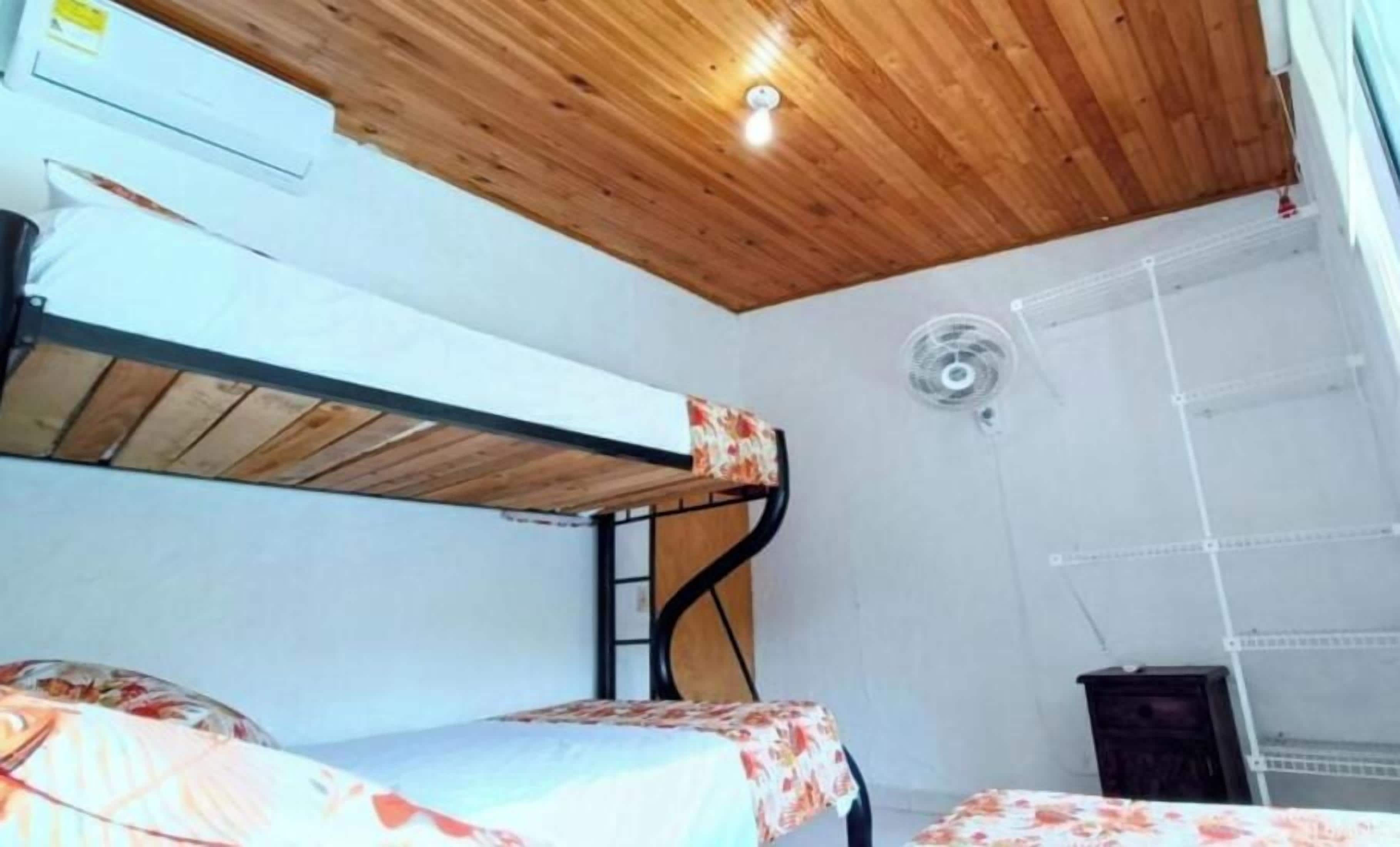 Et værelse med køjesenge, ventilator og en hvid væg med hylde.