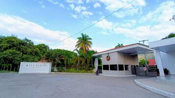 A gated entrance with a sign reading 'San Marcos,' a covered area with a roof, and a motorcycle parked in front.