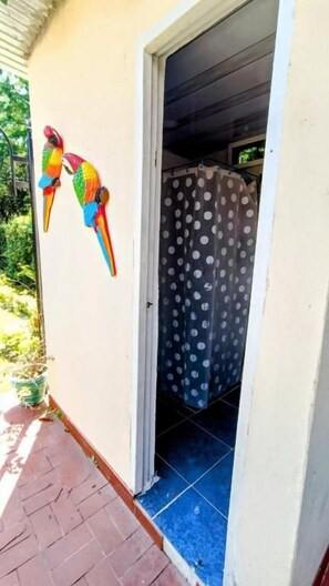 A doorway to a room with a polka dot shower curtain, a potted plant, and a colorful bird decoration. -  Villa Marfelia Spa (Ricaurte)