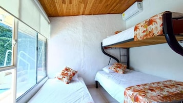 Habitación con literas, ventana, paredes blancas y techo de madera.