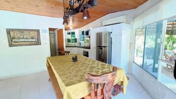 Un comedor con una mesa, sillas, una araña y una cocina al fondo.