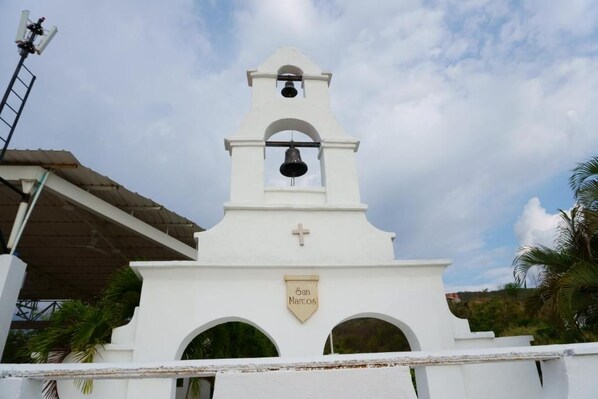 Una iglesia blanca con un campanario, una cruz y un cartel que dice 'San Marcos'.