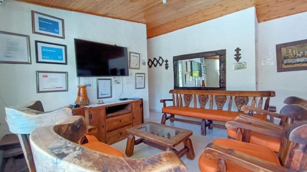 A living room with a television, wooden furniture, and framed certificates on the wall.