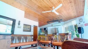 A room with wooden ceiling and walls, a ceiling fan, and multiple wooden chairs.