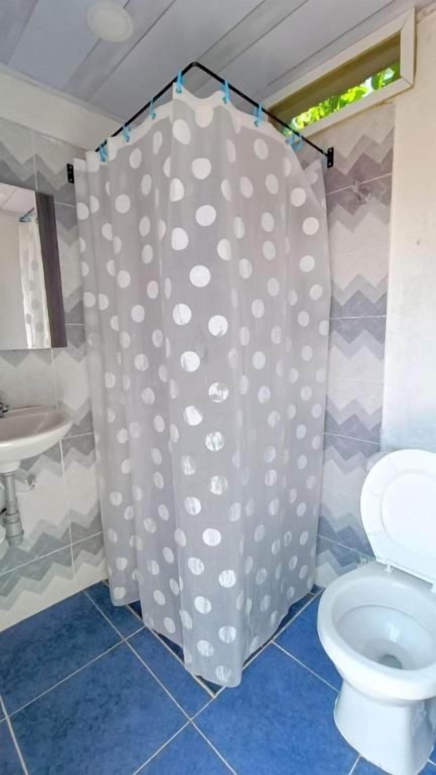 A bathroom with a shower curtain, a sink, and a toilet.