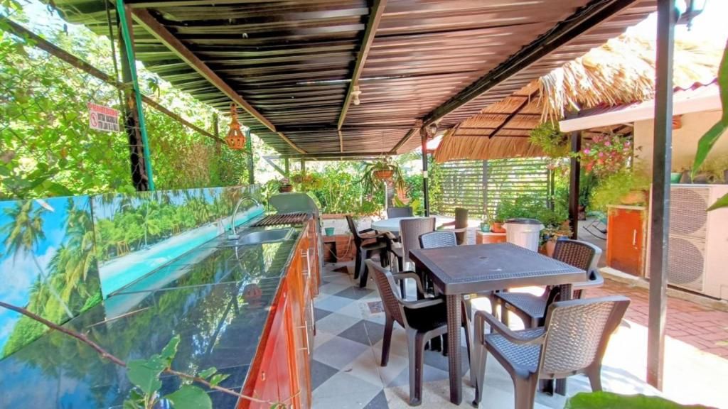 Un patio al aire libre con una mesa de vidrio, sillas y una parrilla.