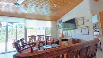 Habitación con techo de madera, ventanas amplias y televisor en la pared.