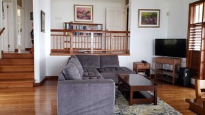 Una sala de estar con un sofá gris, una mesa de centro, un mueble para televisión y una estantería.