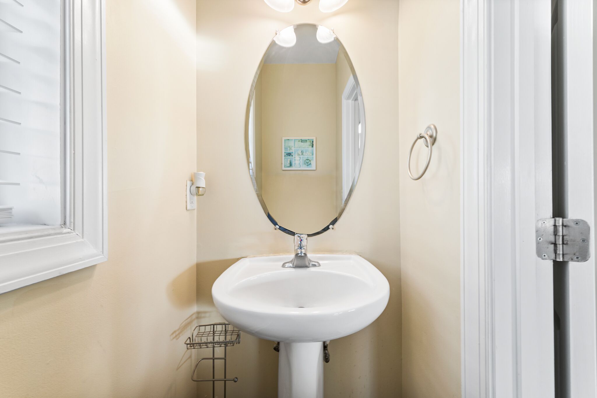 A bathroom with a white sink, a mirror, and a light fixture above the mirror.