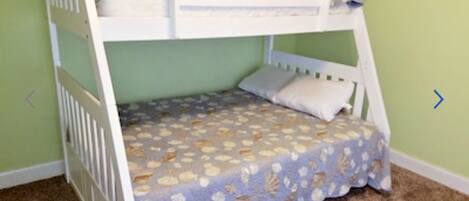 A bunk bed with a patterned bedspread and pillows, set against a green wall.