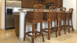 A kitchen with a stainless steel refrigerator, a microwave, and a built-in water dispenser. There are four wicker bar stools with a woven seat and backrest. - BeachFront, Golf, Heated pool, Tennis,Netflix, Gym, Pickleball (La Paz)
