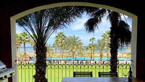 A balcony with a view of the ocean, palm trees, and a pool. - BeachFront, Golf, Heated pool, Tennis,Netflix, Gym, Pickleball (La Paz)