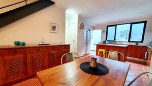 A dining area with a wooden table, chairs, and a kitchen in the background. - Charming Townhouse in the Heart of Fremantle (Fremantle)
