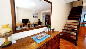 A wooden console table with a mirror, a television, and a "Welcome" sign. A staircase is visible in the background. - Charming Townhouse in the Heart of Fremantle (Fremantle)