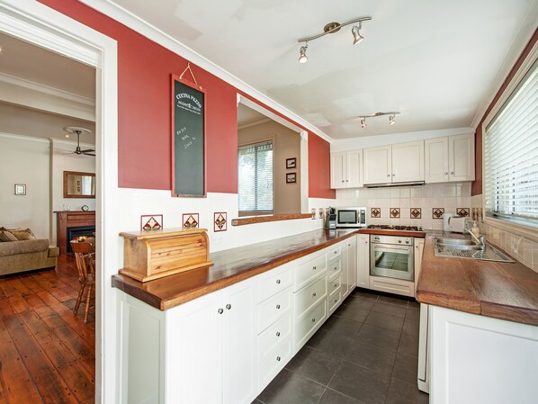 A modern kitchen with white cabinets, a wooden countertop, and a chalkboard sign.