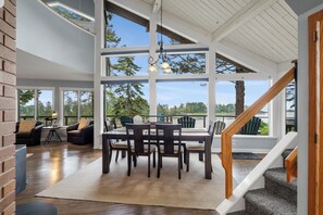 A spacious room with a dining table, chairs, and a staircase leading to an upper level.