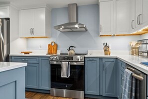 A modern kitchen with stainless steel appliances, a built-in oven, and light blue cabinetry.