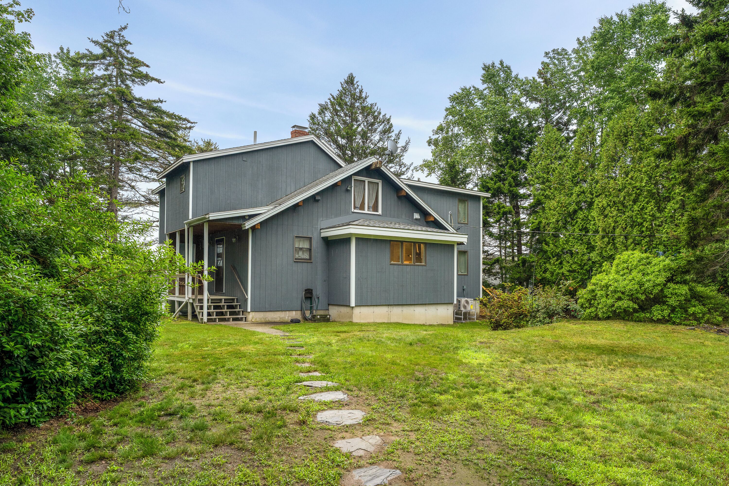 A two-story house with a covered porch, a stone pathway leading to the front door, and a well-maintained lawn.