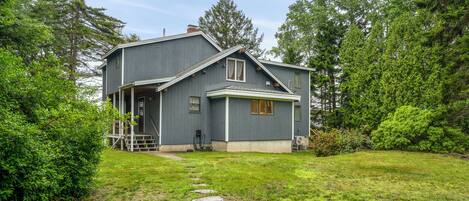 A two-story house with a covered porch, a stone pathway leading to the front door, and a well-maintained lawn.