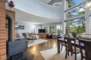 A spacious living room with a fireplace, a television, and a large window overlooking a natural landscape.