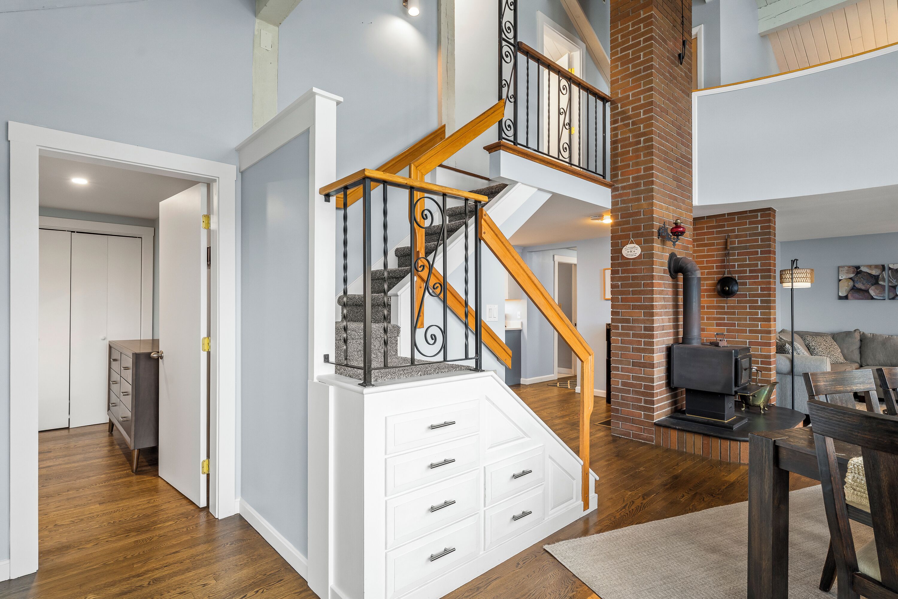 A multi-level home interior with a staircase, wooden flooring, and a brick fireplace.