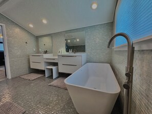 Une salle de bain moderne avec une baignoire sur pieds, un grand miroir et un meuble-lavabo.
