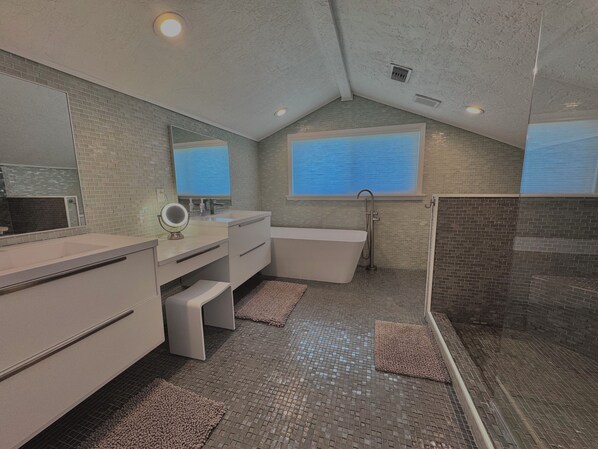 A modern bathroom with a freestanding bathtub, a large mirror, and a shower area.