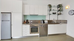 A modern kitchen with white cabinets, stainless steel appliances, and a built-in shelf with plants. - Ultimate 2-Bed Apartment in Surry Hills - Ultimate Convenience (Surry Hills)